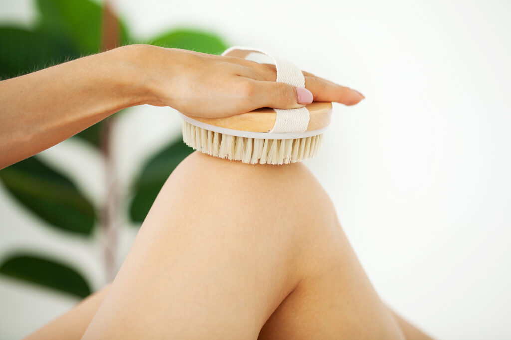 Woman's,Arm,Holding,Dry,Brush,To,Top,Of,Her,Leg,